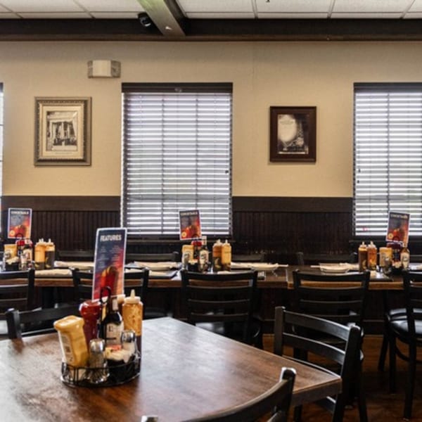 Interior of Half Moon Restaurant & Brewery, featuring wooden tables, chairs, and condiments, with blinds on windows.